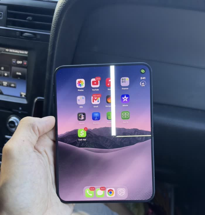 A hand holds an unfolded phone with a bright vertical white line and a horizontal line across its inner display.